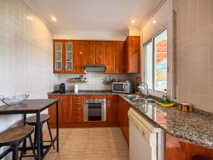 a kitchen with wooden cabinets and a counter top at Villa Claudia by Hello Homes Sitges in Sitges