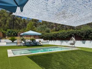 a swimming pool in a yard with a large umbrella at Villa Claudia by Hello Homes Sitges in Sitges