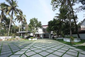 a courtyard with palm trees and a building at Bright Nest Service Villa Munroe in Kollam