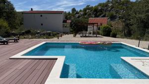 a swimming pool in a yard with a wooden deck at Private Villa Bonaventura with Pool & Jacuzzi & BBQ for Families & Groups near Split in Donja Mala