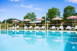 a swimming pool with chairs and umbrellas on the side at Chianti Village - Free Parking & Pool in Tavarnelle Val di Pesa