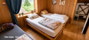 two beds in a small room with a window at Vilimu Sodyba - Stone Hall in Kriukai