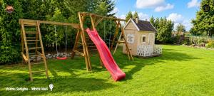 a playground with a slide and a house at Vilimu Sodyba - Stone Hall in Kriukai