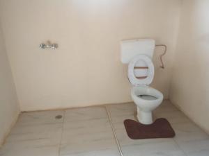a bathroom with a toilet with a rug on the floor at Dewclaw Baobab Safari Lodge in Mfuwe