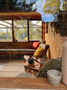 a porch with a couch and a table and windows at The Grasshouse Cabins in Burrawang