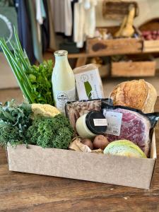 a box of food on a table with vegetables and milk at The Grasshouse Cabins in Burrawang +15 photos