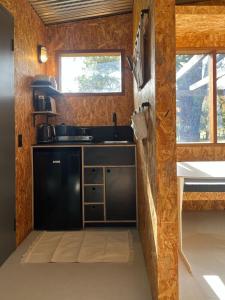a kitchen with a black refrigerator and a sink at The Grasshouse Cabins in Burrawang