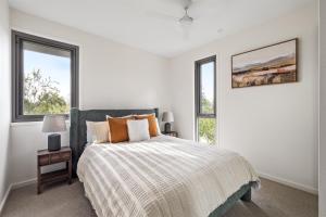 a white bedroom with a bed and two windows at The Cape Collective 6 in Margaret River Town