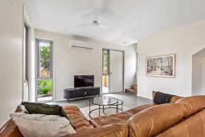 a living room with a brown couch and a tv at The Cape Collective 6 in Margaret River Town