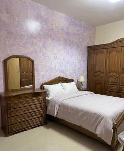 a bedroom with a bed and a purple wall at مراكش تامنصورت in Aït Ali