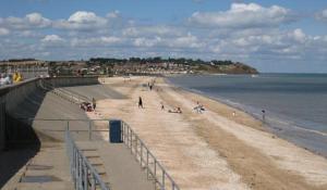 a beach with people on the sand and the water at The Butterfly in Leysdown-on-Sea +2 photos