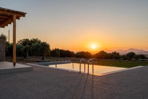 a pool with the sunset in the background at Ampeli Residences-Sea view-Private Pool in Zipárion