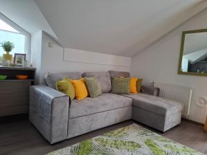 a gray couch with colorful pillows in a living room at Lemon Garden Villapark in Bükfürdő