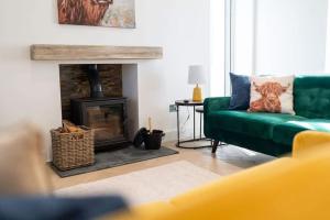 a living room with a green couch and a fireplace at Easter Cottage -4 Bed Converted Barn Cottage in Turriff