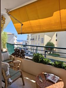 a balcony with a yellow umbrella and a table and chairs at Cannes à Pied in Cannes
