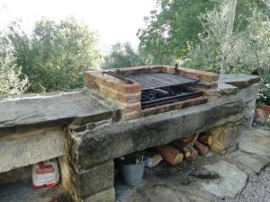 an outdoor brick oven with a grill and logs at Villa Ceppeto in Monte San Savino