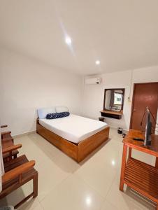a bedroom with a bed and a television in it at ฤทัยลอดจ์ in Ban Tao Than