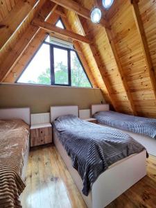 two beds in a room with a wooden ceiling at U seymura qecres in Qǝçrǝş