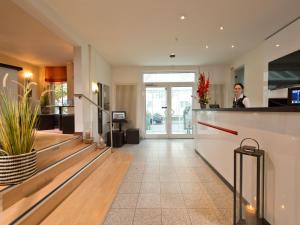 a woman standing at a counter in a hotel lobby at ACHAT Hotel Dresden Elbufer in Dresden