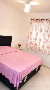 a bedroom with a pink bed and two windows at Unamar Beach in Cabo Frio
