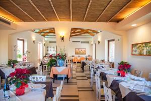 ein Esszimmer mit weißen Tischen und Stühlen mit roten Blumen in der Unterkunft Alle Querce Hotel Ristorante in Castelbuono