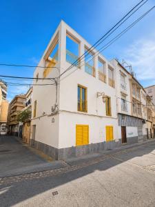 a white building with yellow doors on a street at Casa Soleá- a dos min de la playa in Castell de Ferro