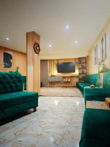 a living room with green couches and a flat screen tv at Modern Palace Dawassah in Al Mawşil