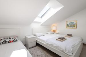 a white bedroom with two beds and a skylight at Apartments 2A in Petrcane