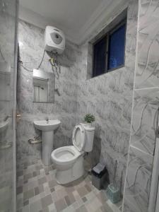 a bathroom with a toilet and a sink at Monroe Luxury Apartments in Kumasi +13 photos