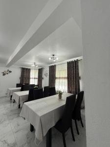 a dining room with white tables and black chairs at Vila MaeStar in Curtea de Argeş