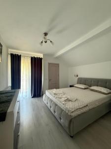 a white bedroom with a large bed and a window at Vila MaeStar in Curtea de Argeş