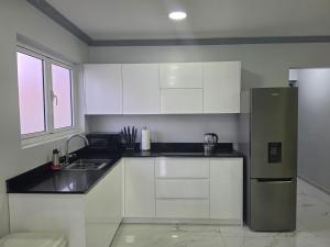 a kitchen with white cabinets and a stainless steel refrigerator at New Modern Apartment in Willemstad