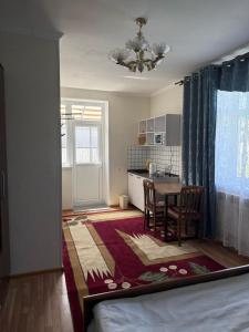 a room with a bed and a table and a kitchen at Yhome in Karakol