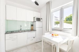 a kitchen with white cabinets and a table and a window at Apartments 2A in Petrcane