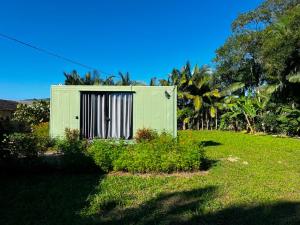 a green building with a door in a yard at Recanto Contêiner Apiúna in Apiúna