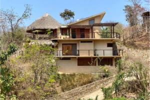 a house on top of a hill with trees at Casa Monte Pacífico, jacuzzi, wifi Starlink y vista al mar in San Agustinillo