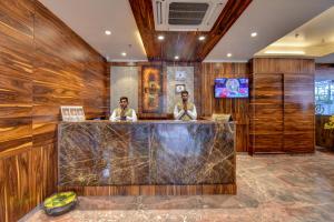 two men sitting at a bar in a hotel lobby at Hotel Bhagyalaxmi NX in Shirdi