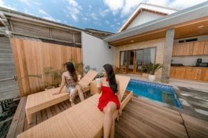two women sitting on a deck next to a swimming pool at Sunrise Cottage in Nusa Penida +159 photos