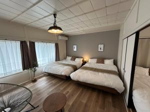 two beds in a room with a table and chairs at koharubi hanada in Murochō