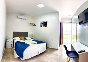 a bedroom with a bed and a desk and a chair at Pousada Mar de Luna in Penha