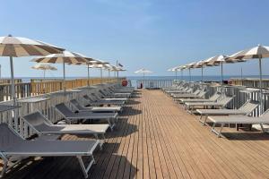a row of lounge chairs and umbrellas on a beach at Four Points by Sheraton Catania Hotel in Catania