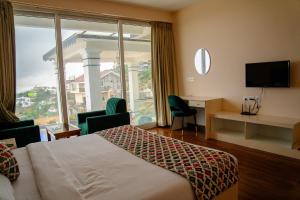 a hotel room with a bed and a large window at Luxe Vista Resort Kodai in Kodaikānāl +91 photos