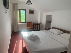 a bedroom with a white bed with towels on it at Pensiunea Valea Pinului in Rau Sadului