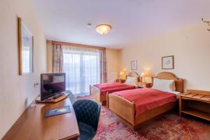 a hotel room with two beds and a television at Hotel-Pension Schwaighofen in Eugendorf