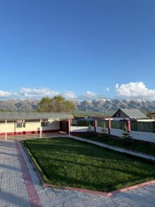 a building with a green yard with mountains in the background at Ayara home in Kyzart +29 photos