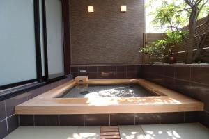 a hot tub in a room with a window at Dogo Onsen Yachiyo 道後温泉八千代 in Matsuyama