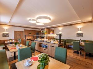 a restaurant with wooden tables and chairs and a kitchen at Hotel-Pension Schwaighofen in Eugendorf