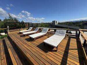 a deck with several white lounge chairs on it at Vivaldi Suites in Villa Carlos Paz