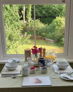 a table with bowls and dishes on it with a window at Watercombe House in Wheddon Cross