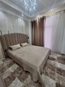 a bedroom with a large bed and a chandelier at Mamura Karimova in Andizhan